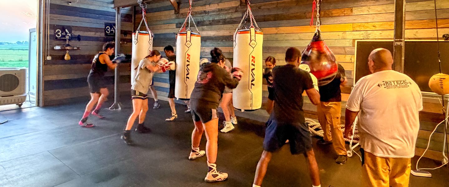 Members working the heavy bag line while a coach looks on