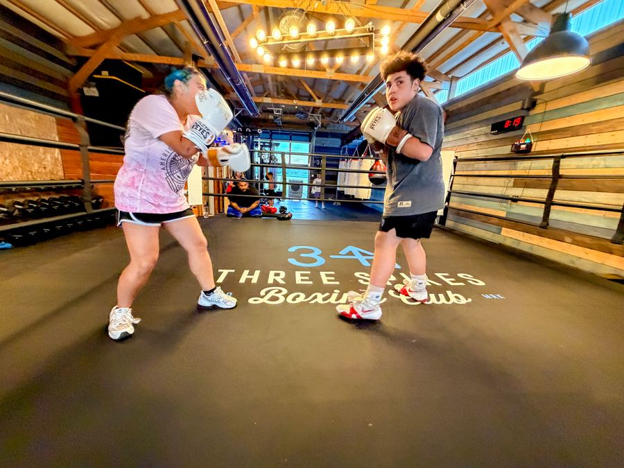 Two young boxers squaring off on the Three Spikes logo in the ring