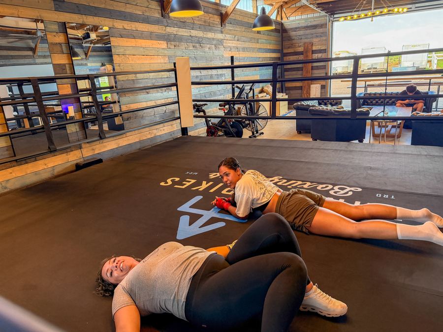 Two members catching their breath on the mat after a hard session