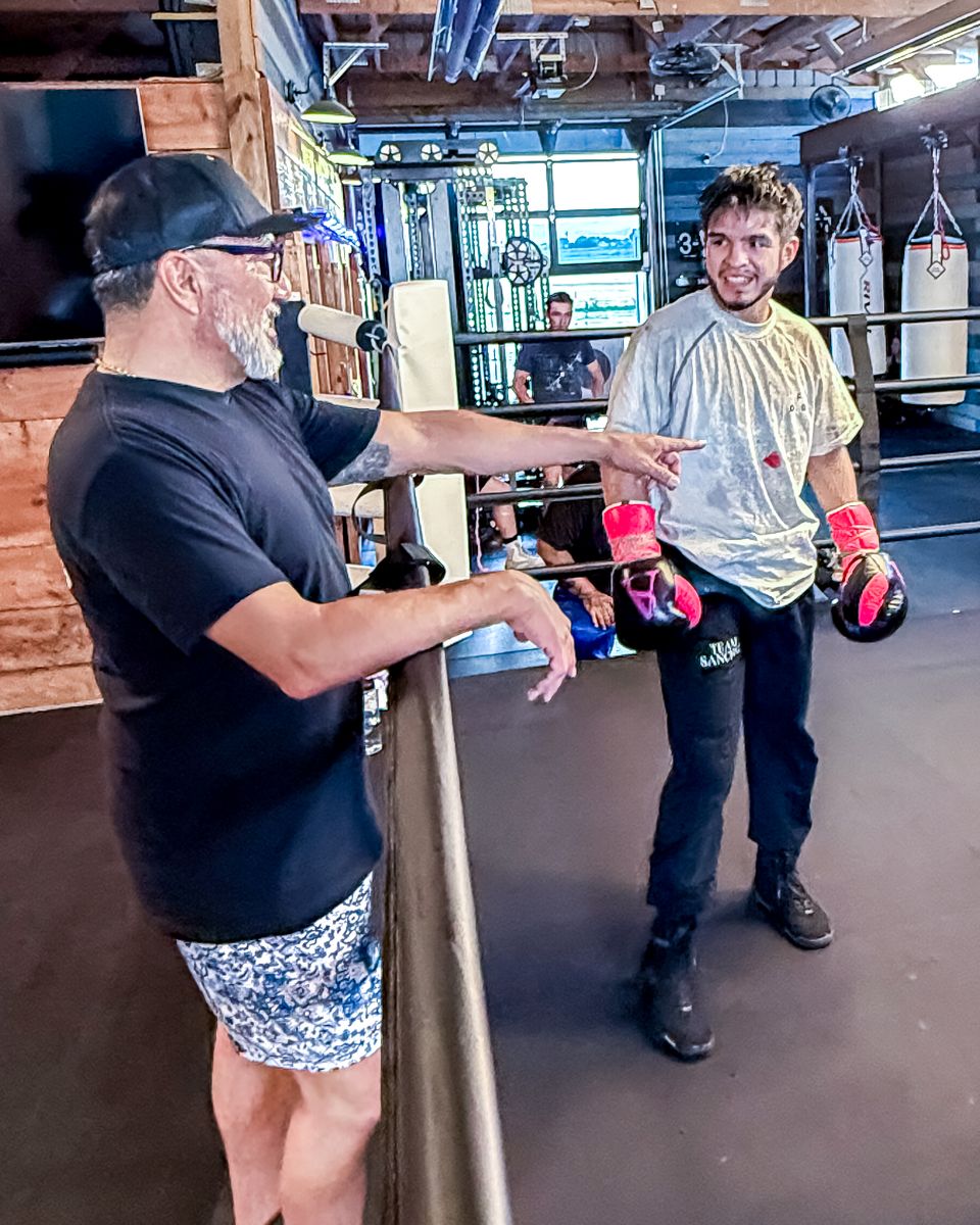 A coach giving instruction to an adult boxer in the ring