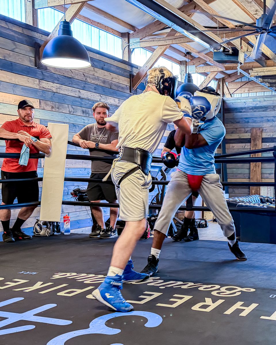 Two boxers in headgear sparring in the ring