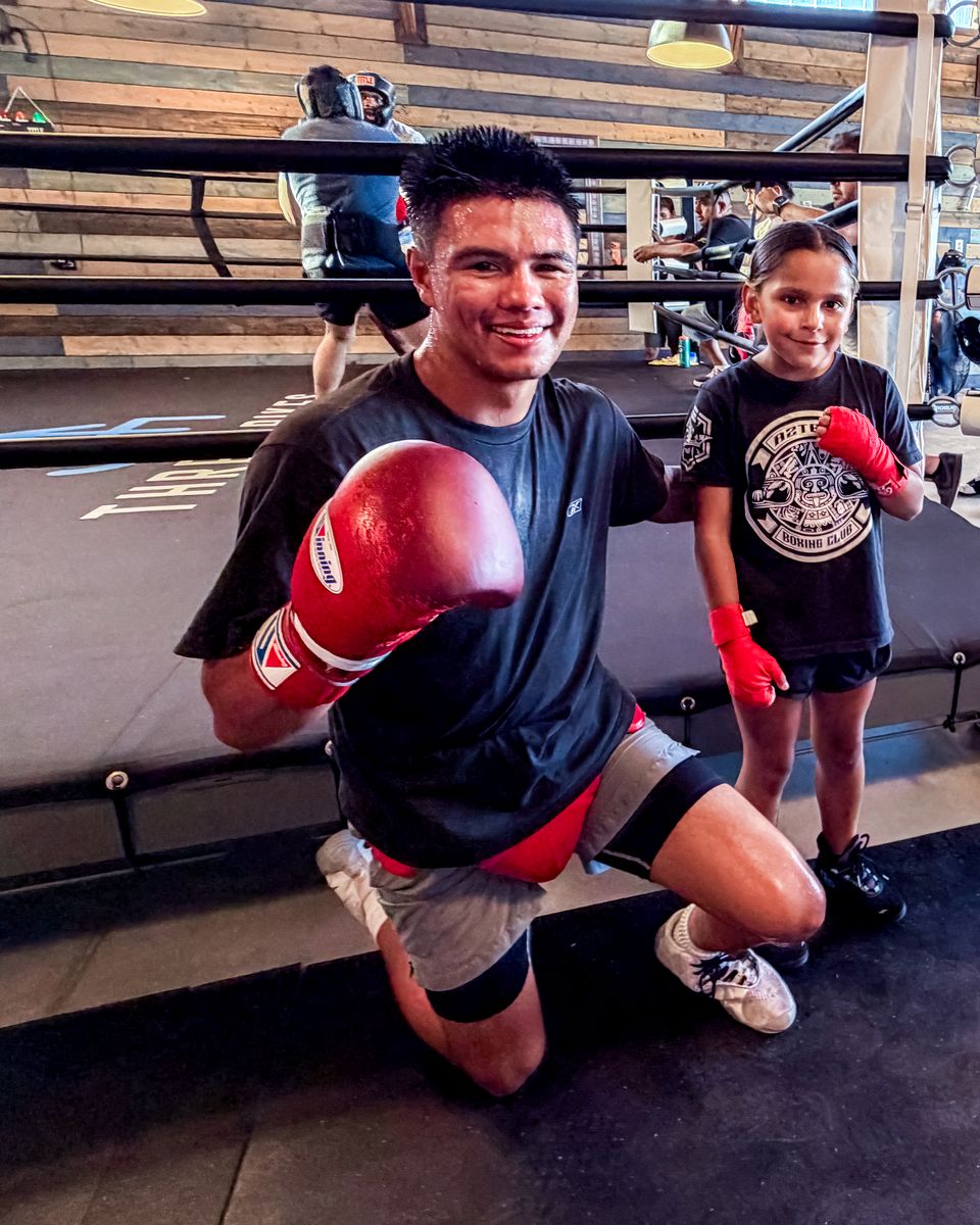 A young boxer and a youth member posing in the ring